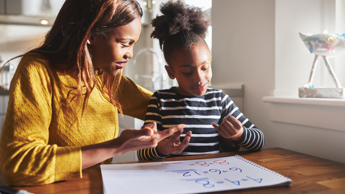 Mother helping daughter with homework at table in bright natural light